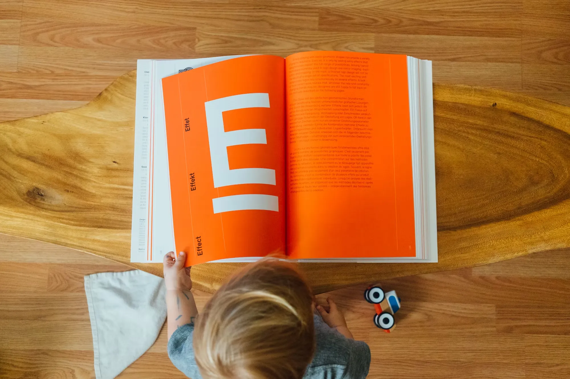 

An image of a young girl sitting at a table with a stack of books, a pencil, and a piece of paper. She is looking thoughtfully at the books, ready to create her own storytelling game using the books as inspiration.