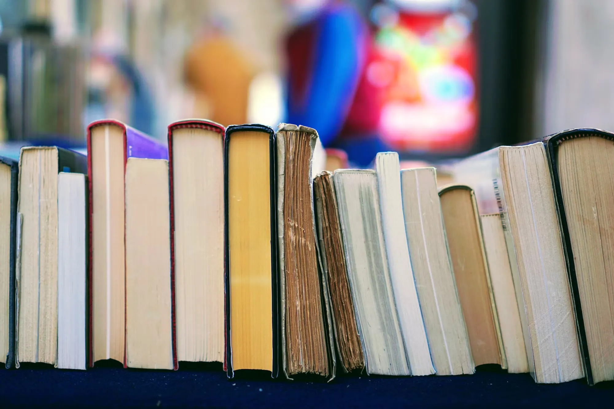 

An image of a smiling child sitting in a cozy chair with a pile of books in front of them. The child is surrounded by a variety of books of different sizes, colors, and genres, suggesting the wide range of options available when choosing